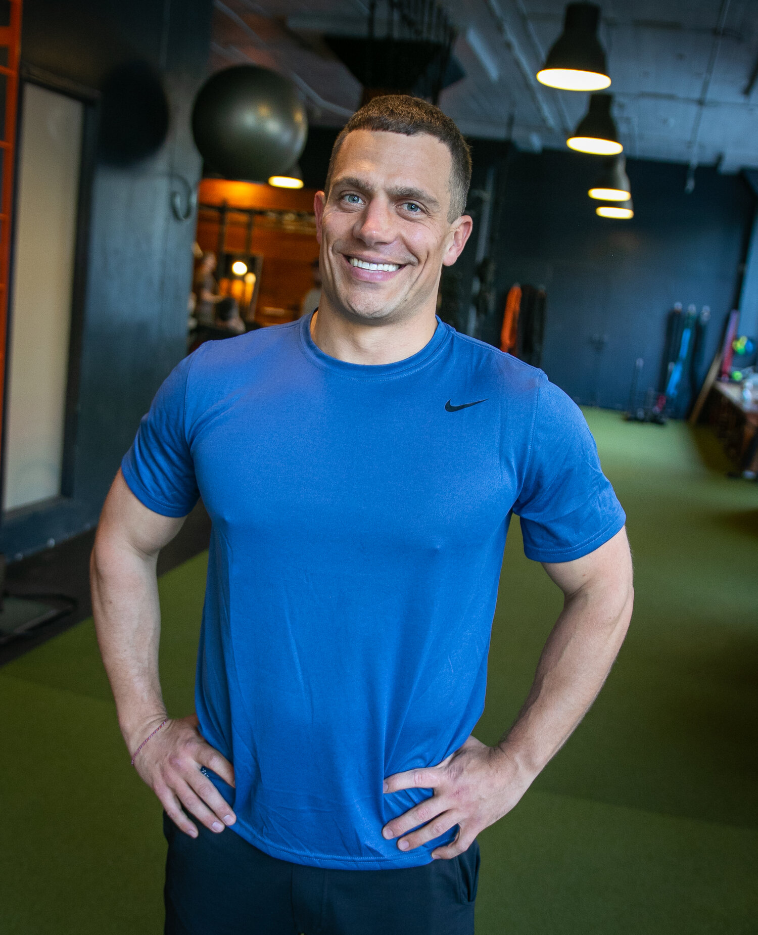 Tycho smiling at the camera, with his hands on his hips, and wearing a blue shirt